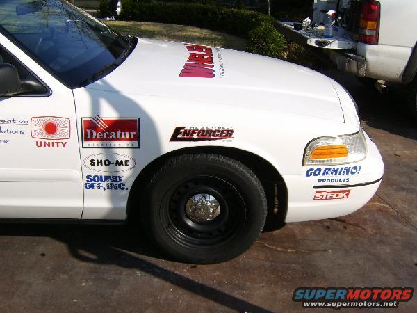 1999 Ford Crown Victoria side view with various decals on fender and door