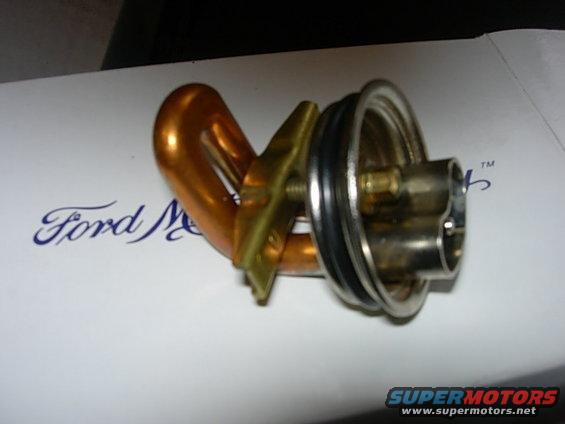 Block heater part with copper tubing and metal flange on white surface with Ford logo