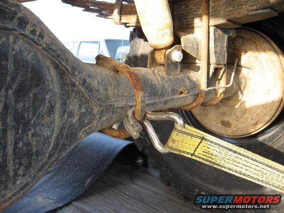 Rear axle and suspension with yellow tie-down strap attached to a D-ring