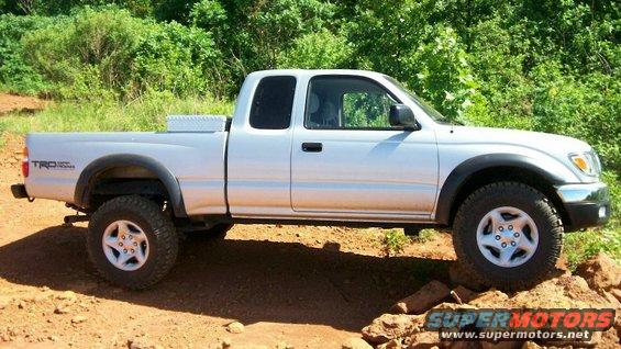 Silver Toyota Tacoma pickup truck with TRD badging, driving on rough terrain