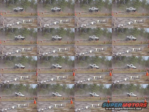 White pickup truck driving on a dirt track with orange cones and checkered flags