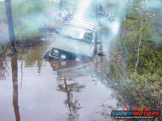 Green SUV stuck in water, front view with auxiliary lights