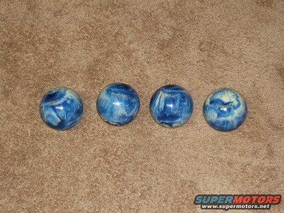 four blue and white swirl bowling balls on a brown carpet