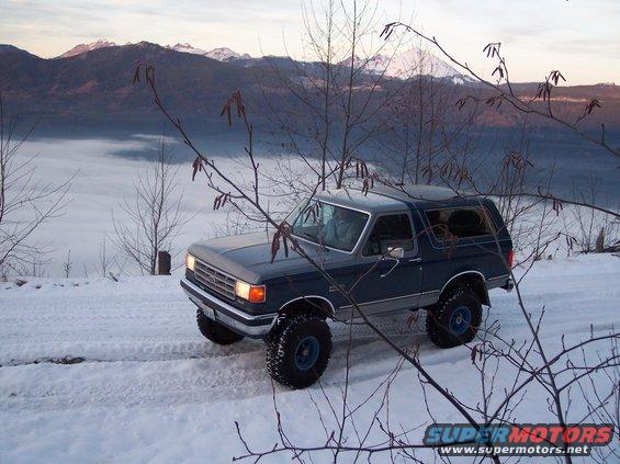 1987 Ford Bronco in snow, grey hood, blue body, 3q-front view