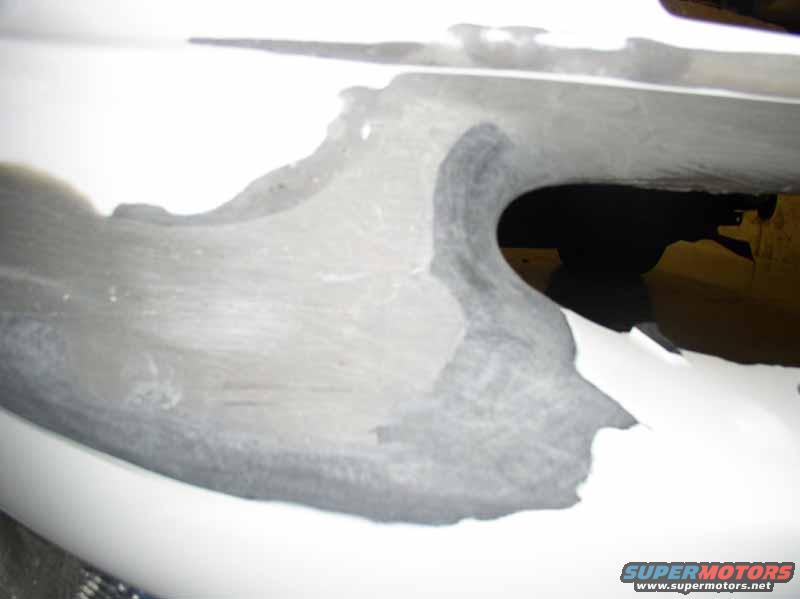 White car bumper with gray primer and damage, close-up