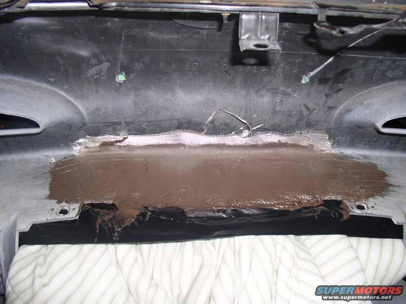 Plastic panel with fiberglass mesh and brown putty applied for repair