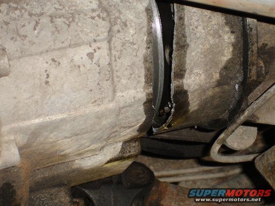 Close-up of a cracked transmission housing with visible damage and fluid leakage