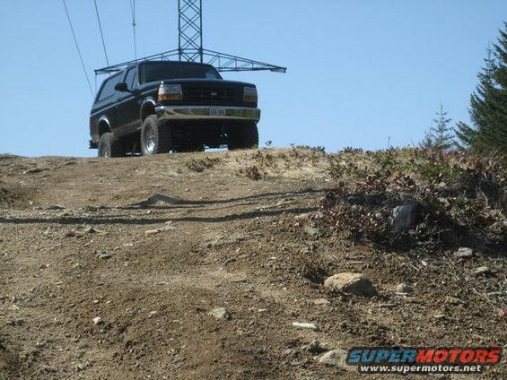 Black 1995 Ford Bronco climbing a dirt hill with power lines overhead