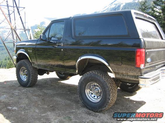black Ford Bronco parked on dirt road with mountains in background