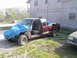 1997 Chevrolet C/K Pickup - A damaged maroon pickup truck sits outside a building, with another vehicle partially visible to the right.