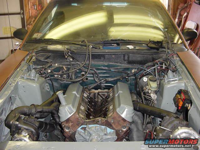 Engine bay with twin turbos and V8 engine. The car is a 1995 Ford Mustang