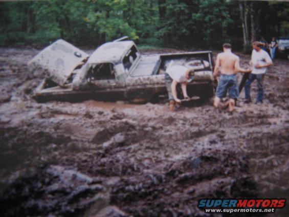 Mud-covered 1977 Ford F-150 stuck in deep mud with hood open