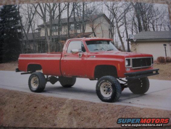Red lifted pickup truck with large tires and a custom bumper
