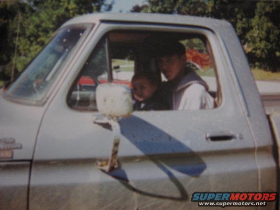 Man driving a 1977 Ford F-150 with a child in the passenger seat