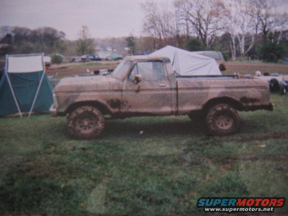 Mud-covered 1977 Ford F-150 pickup truck, side view, with a tarp in the bed
