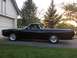 1968 Ford Ranchero - A side view of a black pickup truck with a white trim, parked in a driveway during sunset.