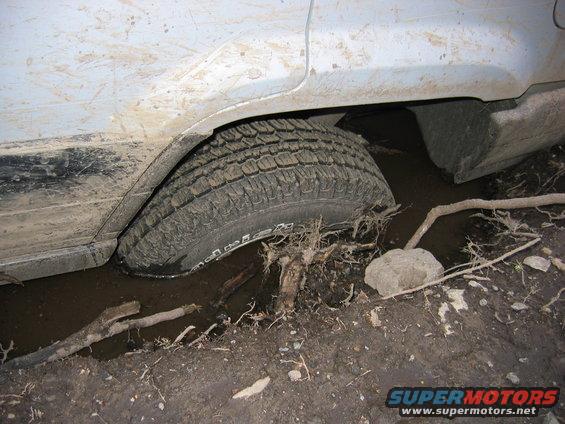 Vehicle tire stuck deep in mud and debris