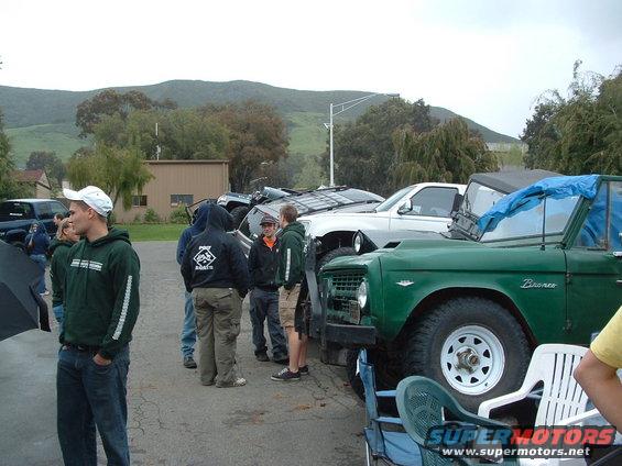 Green Bronco with a blue tarp over the windshield, parked outdoors