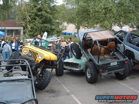 Yellow Jeep and green Suzuki Samurai stacked on top of a car, with another vehicle in the foreground