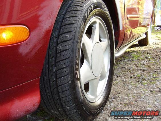 Close-up of a red car's front wheel and fender with a chrome side step visible