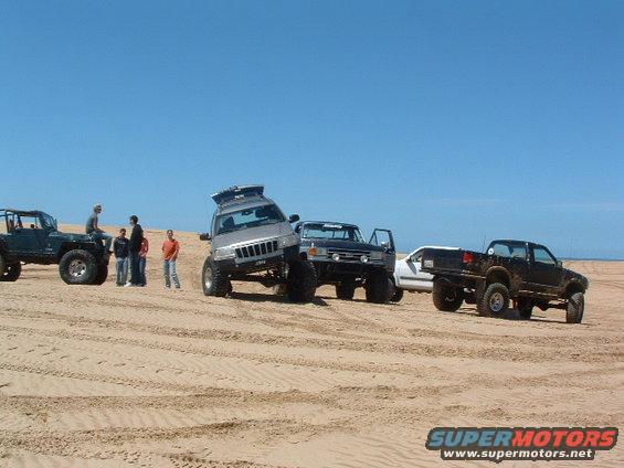 1994 Jeep YJ on sand dunes, silver, with roof rack, tilted