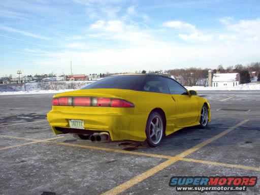 Yellow 1994 Ford Probe with a black roof and dual exhaust pipes, parked in a lot