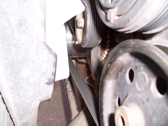 Close-up of engine belts and pulleys, showing ribbed texture and metal components