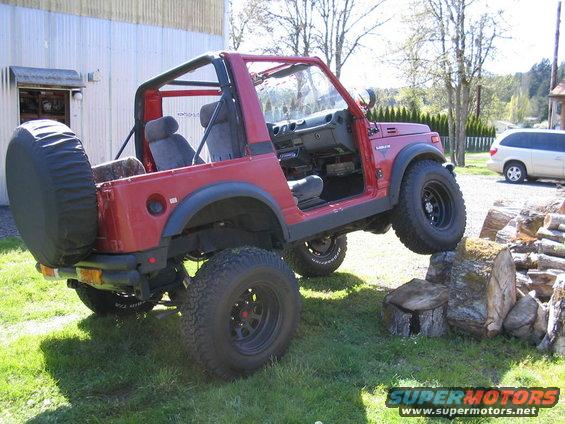 Red Suzuki Samurai with lifted suspension and off-road tires, angled on logs