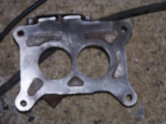 metal gasket with two large circular openings and several bolt holes