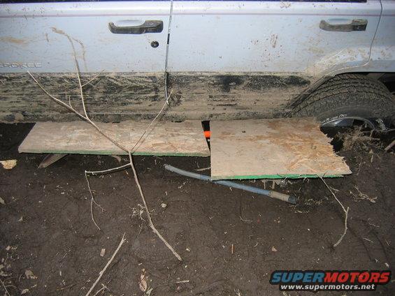 Silver Jeep Cherokee side with mud and plywood under the doors