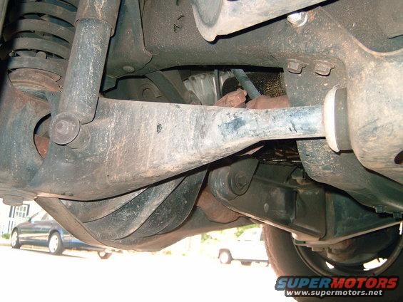 Undercarriage view of suspension components and drivetrain. Two other vehicles visible in background