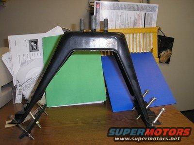 Black metal automotive part with bolts on a desk with papers and folders