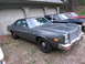 1978 Dodge Monaco - A 1978 Dodge Monaco sedan is parked in front of a garage, with two other vehicles visible behind it.