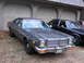 1978 Dodge Monaco - A gray 1977 Dodge Monaco sedan is parked in front of a garage, with another dark sedan visible behind it.