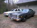 1978 Dodge Monaco - Two sedans are parked on a gravel driveway in front of a garage with a grey roof.
