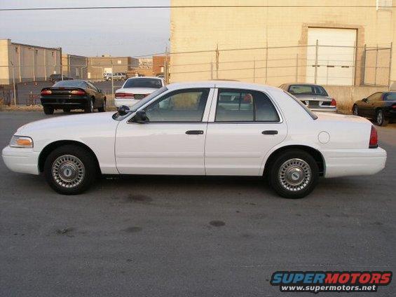 2001 Ford Crown Victoria parked on asphalt, side view. Other cars and buildings in background
