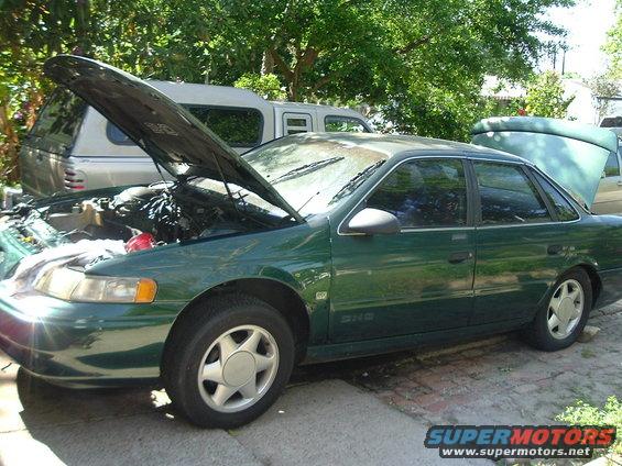 Green 1993 Ford Taurus sedan, hood open, parked outdoors