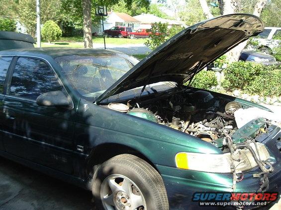 Green sedan, hood open, showing engine. Front passenger side visible