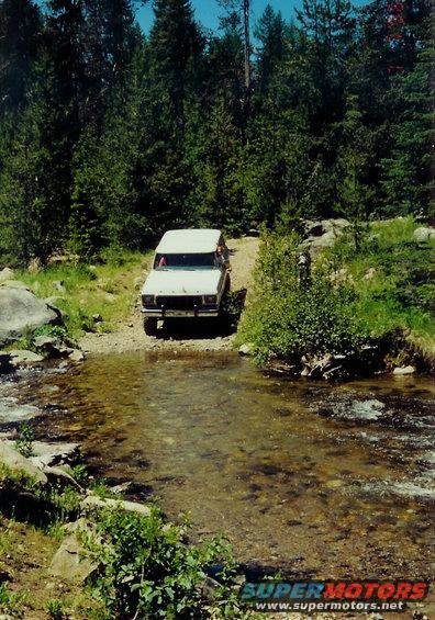 White 1979 Ford Bronco crossing stream