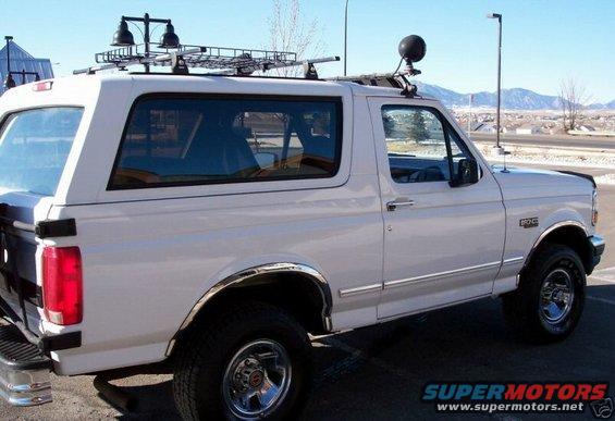 White 1994 Ford Bronco with roof rack, auxiliary lights, and a ball mount on the roof
