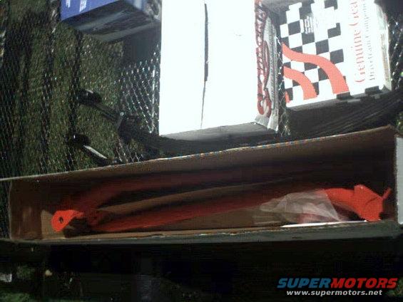 Orange suspension parts in a cardboard box with "Genuine Gear" packaging in the background