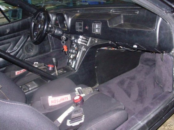 Interior view of a 1972 DeTomaso Pantera, showing racing seats, Simpson harnesses, and a modified dashboard
