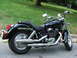 2004 Honda Shadow Sabre VT 1100 - Side view of a black 2004 Honda Shadow Sabre VT 1100 motorcycle parked on a paved surface with grass and a tree in the background.
