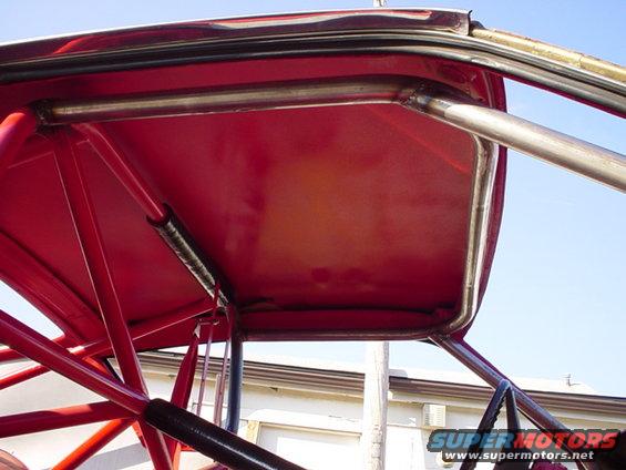Red interior roll cage with metal bars against a blue sky
