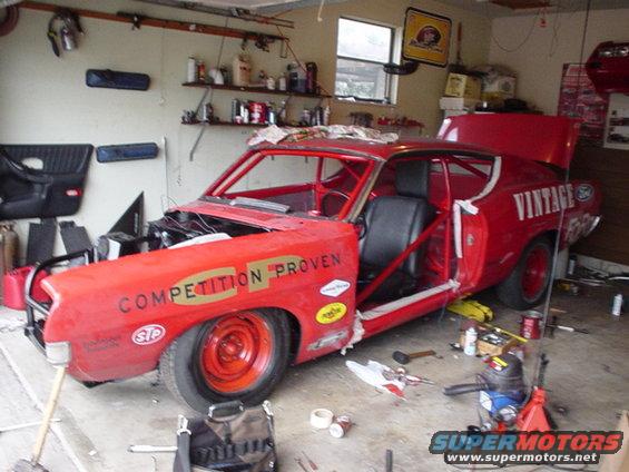 Red 1968 Ford Torino race car in a garage, hood removed, doors open, roll cage visible
