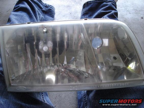 2000 Ford Crown Victoria headlight assembly with visible Ford logo and SAE markings