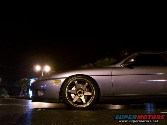 Silver coupe with gold multi-spoke wheels parked at night