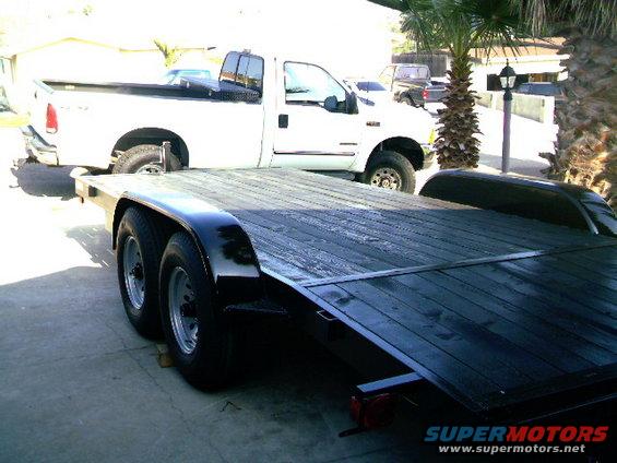 White pickup truck parked next to a black tandem-axle trailer
