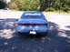 1994 Lincoln Mark VIII - The rear of a blue sedan is shown, parked outdoors with dappled sunlight on the pavement.