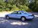 1994 Lincoln Mark VIII - A blue coupe is parked on an asphalt surface with trees in the background.